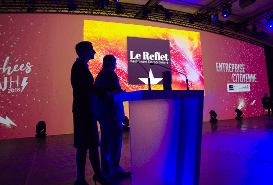Une femme et un homme debout devant un écran